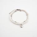 Pulsera plateada con perlas sintéticas y dije de corazón