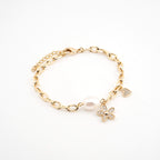 Pulsera dorada con dije de flor y corazón con cristales y una perla sintética